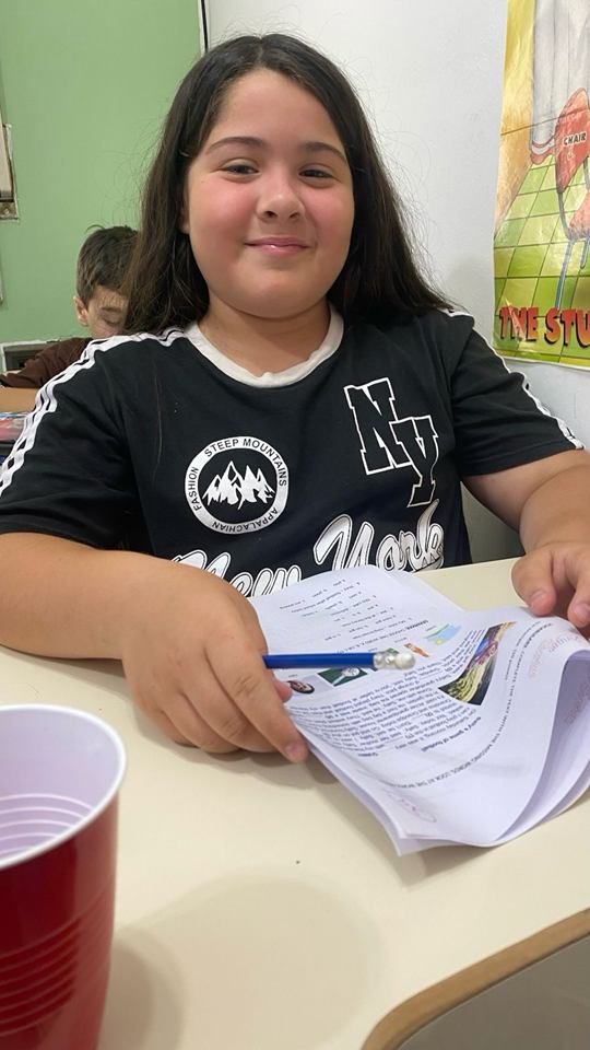 Estudiante sonríe mientras trabaja con sus apuntes en clase