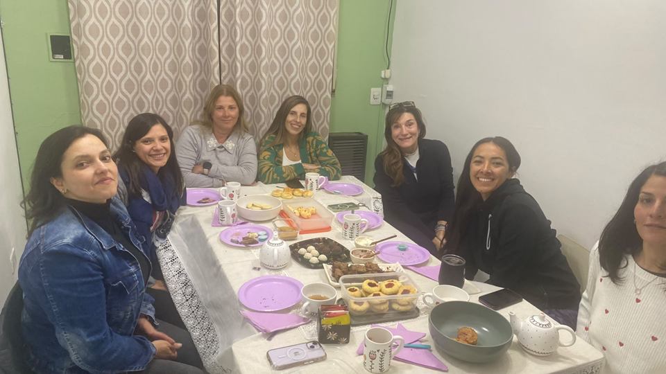 Grupo de estudiantes adultos en un encuentro con comida alrededor de una mesa