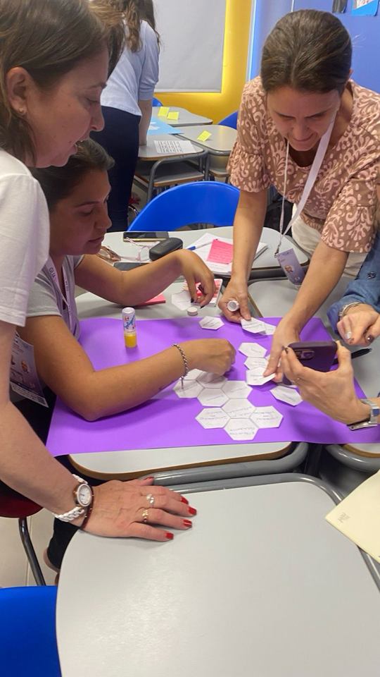 Docentes trabajan en equipo con tarjetas hexagonales durante una capacitación