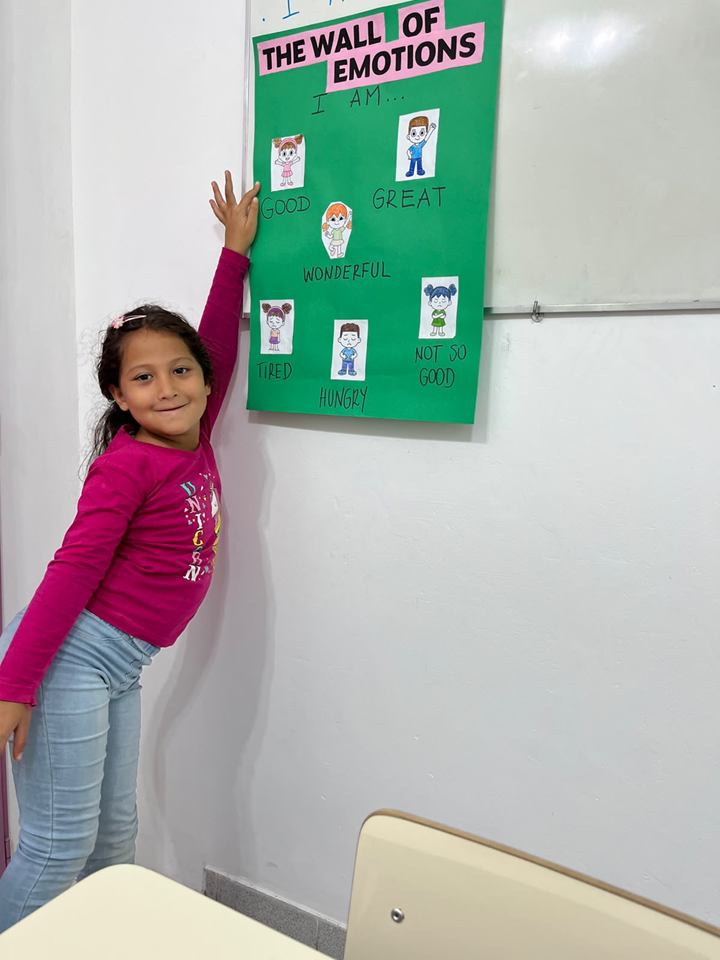 Estudiante señala una emoción en el mural The Wall of Emotions