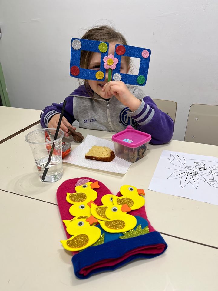 Estudiante con una máscara de colores y un gorro de patitos hechos en clase
