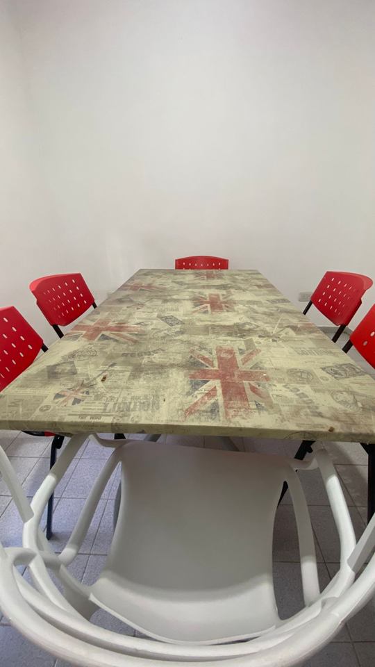 Aula grupal con una mesa decorada con la bandera británica y sillas rojas